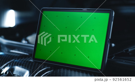 Tablet with green screen on the hood of a car Tablet with green screen on the hood of a car 92561652