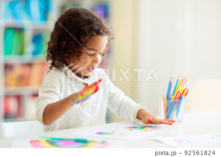 Child drawing rainbow. Paint on hands. Child drawing rainbow. Paint on hands. 92561824