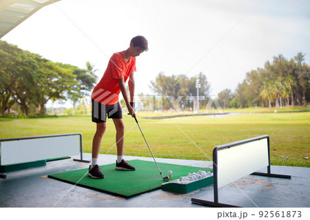 Young man hitting ball on golf driving range. 92561873
