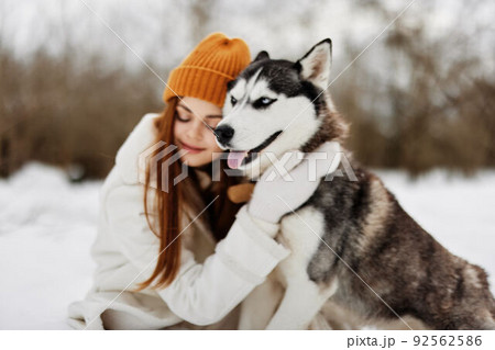 Happy young woman winter clothes walking the dog in the snow winter holidays Happy young woman winter clothes walking the dog in the snow winter holidays 92562586