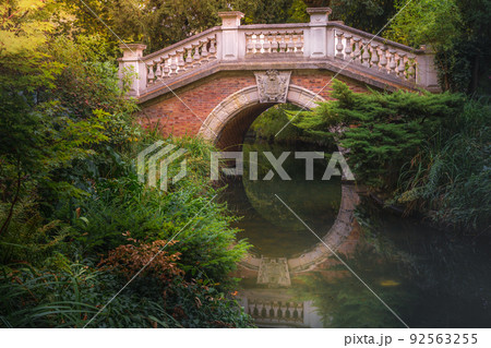 Bridge above pond with reflection in Parc Monceau, Paris, France 92563255