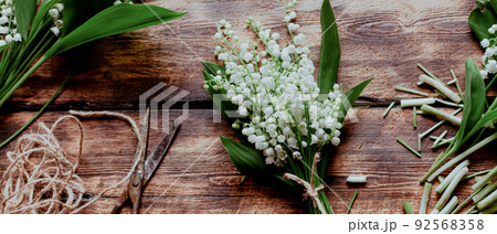 Background from brown wooden boards with forest flowers of lilies of the valley. Photo banner with a place for the inscription 92568358
