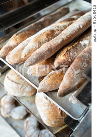 Finished French bread in the bakery on the racks. Baguettes, rustic bread, crown of kings Bordeaux. Vertical photo. 92568418