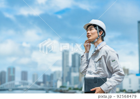屋外で働くヘルメットを付ける若いエンジニア 92568479
