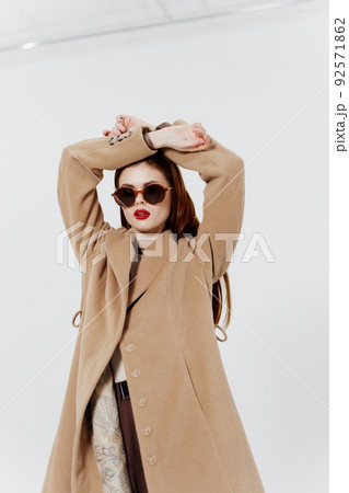 A red-haired professional model poses for a clothing brand magazine in a coat and glasses 92571862