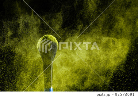 Shaking off yellow powder from a brush on a black background. Shaking off yellow powder from a brush on a black background. 92573091