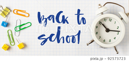 Back to school. Handwritten inscription. School supplies on white checkered paper Back to school. Handwritten inscription. School supplies on white checkered paper 92573723