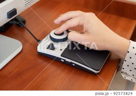 A woman uses a special magnification device for the visually impaired. 92573824