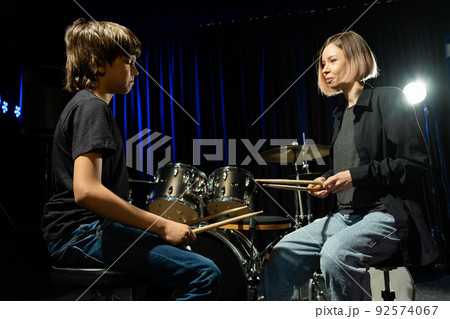 Young woman teaching boy to play drums. 92574067