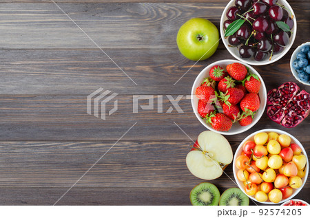 Mix of fresh berries, nuts and fruits. Healthy food contains a lot of vitamins and useful trace elements.Brown wooden background. Copy space. 92574205