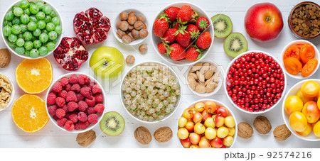Fresh berries, fruits, nuts on a white wooden background. The concept of healthy eating. Food contains vitamins and trace elements 92574216