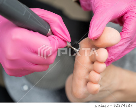 Woman on professional pedicure procedure by abrasive disc machine in beauty salon. Woman on professional pedicure procedure by abrasive disc machine in beauty salon. 92574237