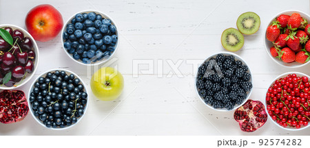 Fresh berries, fruits, nuts on a white wooden background. The concept of healthy eating. Food contains vitamins and trace elements. Copy space. 92574282