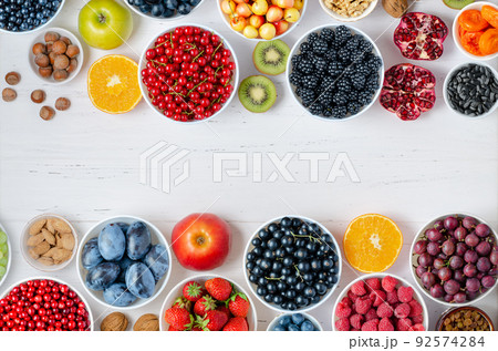 Fresh berries, fruits, nuts on a white wooden background. The concept of healthy eating. Food contains vitamins and trace elements. Copy space. Fresh berries, fruits, nuts on a white wooden background. The concept of healthy eating. Food contains vitamins and trace elements. Copy space. 92574284