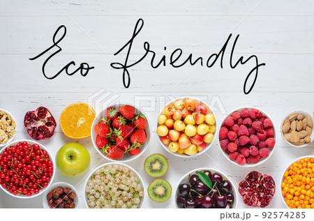 Fresh berries, fruits, nuts on a white wooden background. The concept of healthy eating. Food contains vitamins and trace elements. Eco friendly - handwritten inscription. 92574285