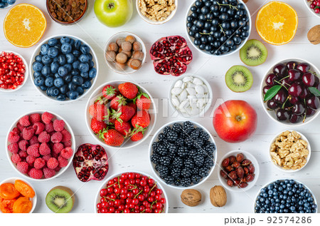 Fresh berries, fruits, nuts on a white wooden background. The concept of healthy eating. Food contains vitamins and trace elements 92574286