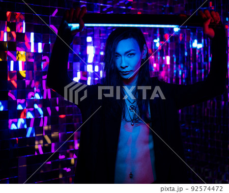 Portrait of a transgender model with a naked torso in a studio with neon lighting. 92574472