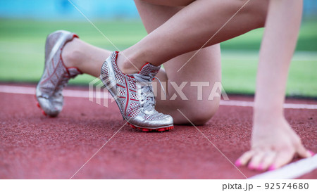 Close-up of female legs. The runner in the stadium is ready for the race. Close-up of female legs. The runner in the stadium is ready for the race. 92574680
