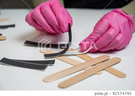 Manicurist in pink gloves uses disposable nail files. Manicurist in pink gloves uses disposable nail files. 92574793