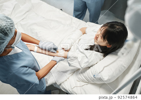 Horizontal high angle view shot of young Asian woman getting intravenous therapy in emergency room 92574864