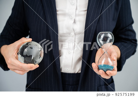 Business woman holding crystal globe and hourglass.  92575199