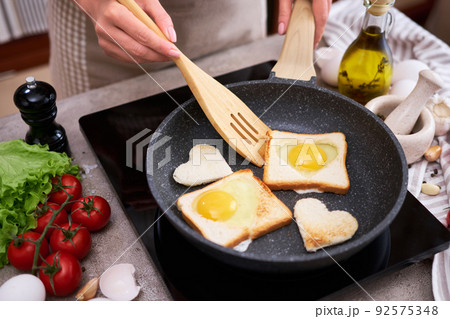 Fried egg Toasts with heart shaped holes on frying pan Fried egg Toasts with heart shaped holes on frying pan 92575348