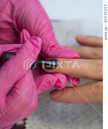 A man on a manicure procedure paints his nails black in a beauty salon A man on a manicure procedure paints his nails black in a beauty salon 92575357
