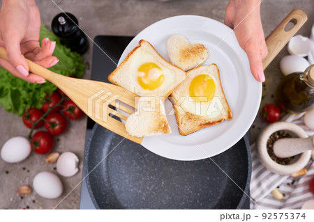 Fried egg Toasts with heart shaped holes on frying pan Fried egg Toasts with heart shaped holes on frying pan 92575374