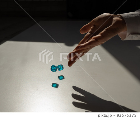 Woman throws a pair of blue transparent dice.  92575375