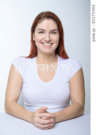 Portrait of a redhead woman with tapes on skin color face for rejuvenation. An alternative way to fight wrinkles. 92575403