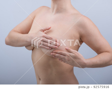 Caucasian woman self checks for breast cancer on white background.  92575916