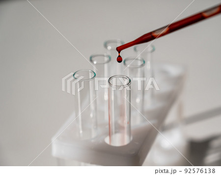 Close-up of a laboratory assistant dripping blood from a pipette into a test tube. Close-up of a laboratory assistant dripping blood from a pipette into a test tube. 92576138