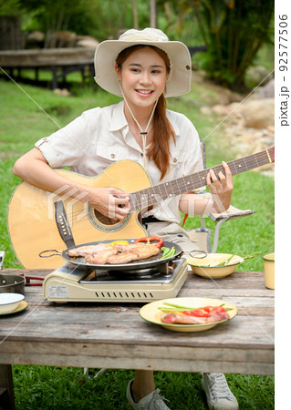 Asian female camper traveler playing her acoustic guitar while camping with her friends 92577506