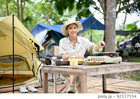Asian female enjoy camping at the campsite, cooking her tasty lunch with the picnic equipments. Asian female enjoy camping at the campsite, cooking her tasty lunch with the picnic equipments. 92577554