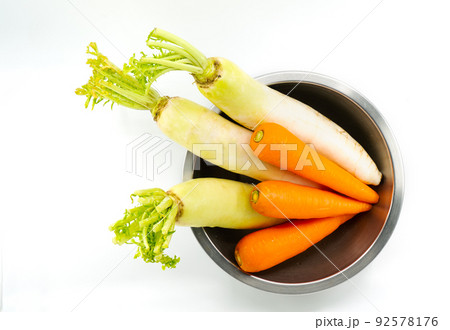 Organic carrots and white radishes in round shape stainless steel bowl, unpeeled carrots and radishes, top view image, isolated image on white background. 92578176