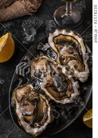 Fresh oysters close-up on ice served with lemon and wine. Fresh oysters close-up on ice served with lemon and wine. 92578230