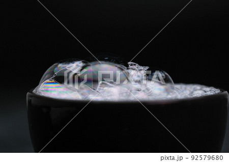 Black cup with foam water and bubbles on black background. Soap bubbles in motion background. 92579680