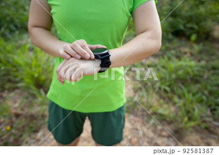 Woman trail runner set the sports watch in forest Woman trail runner set the sports watch in forest 92581387