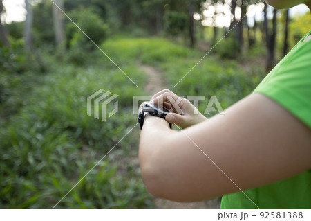 Woman trail runner set the sports watch in forest Woman trail runner set the sports watch in forest 92581388