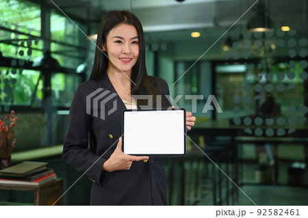 Confident millennial woman in business suit holding digital tablet, empty screen for your advertise text 92582461