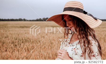 Beauty romantic girl outdoors. Happy young woman in sun hat in summer wheat field at sunset. Copy space, sunset, flare light, summer season. Boho chic style. Beauty romantic girl outdoors. Happy young woman in sun hat in summer wheat field at sunset. Copy space, sunset, flare light, summer season. Boho chic style. 92582772
