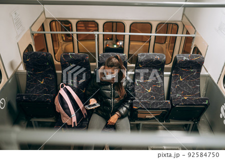 Young woman with mask traveling in the public transport. 92584750