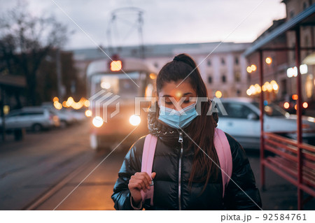 Young student woman in medical mask outdoors with a backpack 92584761