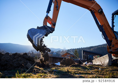 Excavator excavate earth at construction site in the evening. 92584916