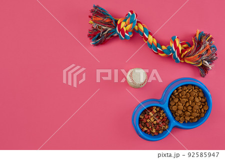 Toys -multi coloured rope, ball and dry food. Accessories for play on pink background top view Toys -multi coloured rope, ball and dry food. Accessories for play on pink background top view 92585947