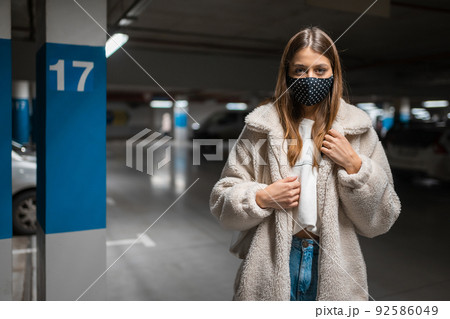 Fashionable young woman in mask at the undreground parking of mall. Pandemic woman concept 92586049