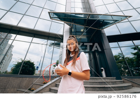 Sportswoman against modern building background outdoors walks in city 92586176