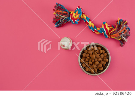 Toys -multi coloured rope, ball and dry food. Accessories for play on pink background top view Toys -multi coloured rope, ball and dry food. Accessories for play on pink background top view 92586420