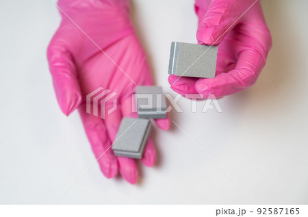 Manicurist in pink gloves holding nail files.  92587165