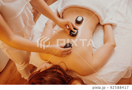 Woman making massages by lava stones in a beauty saloon, lifestyle and healthcare concept Woman making massages by lava stones in a beauty saloon, lifestyle and healthcare concept 92588417